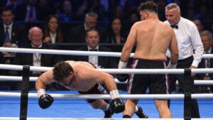 Thomas Carty falls through the ropes as Dave Allen stands nearby during their heavyweight fight