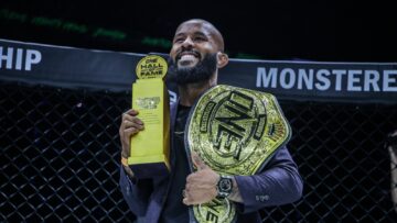 Demetrious Johnson holding his ONE championship belt and Hall of Fame trophy in an archive photograph