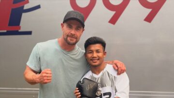 Chris Hemsworth and Rodtang Jitmuangnon pose with a personalized boxing glove at the Extraction 3 set